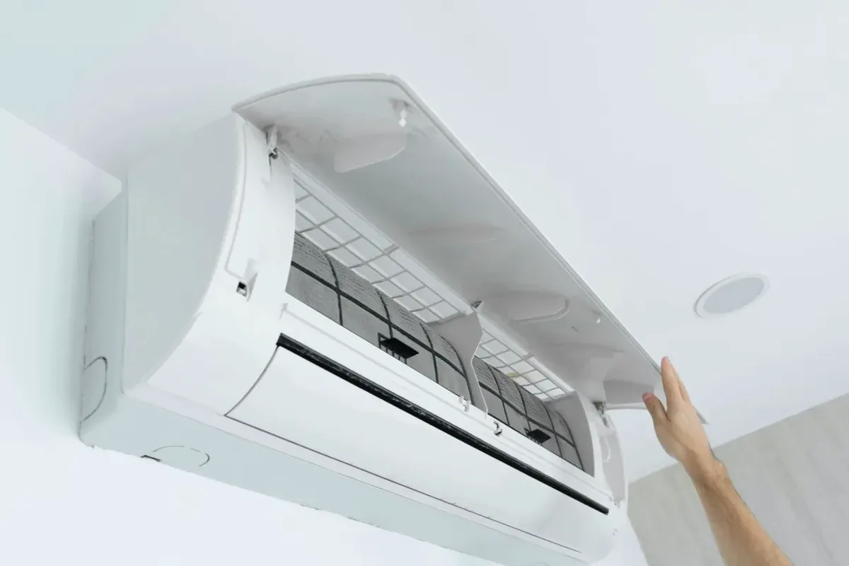 Hand opening the cover of a wall-mounted ductless air conditioner